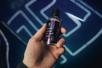 Hand holding a small bottle of Fresh Coat Elite Ceramic Coating with a dark label against a blue background